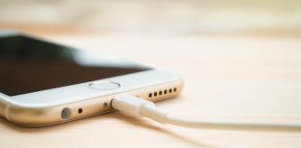 CHIANGRAI, THAILAND -JULY 28, 2016: Close-up image of the Apple iPhone 6S charging with Lightning USB cable on the wooden table with copy space and blurry background on July 28, 2016 in Chiangrai Thailand.